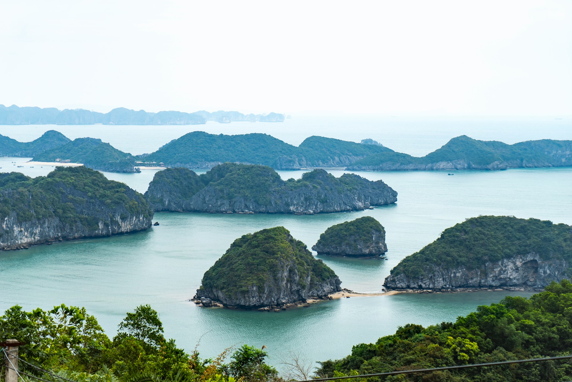 A panoramic view of limestone islands and turquoise waters from the Cat Ba coastal cliff road - an essential stop on the Cat Ba island loop motorbike guide